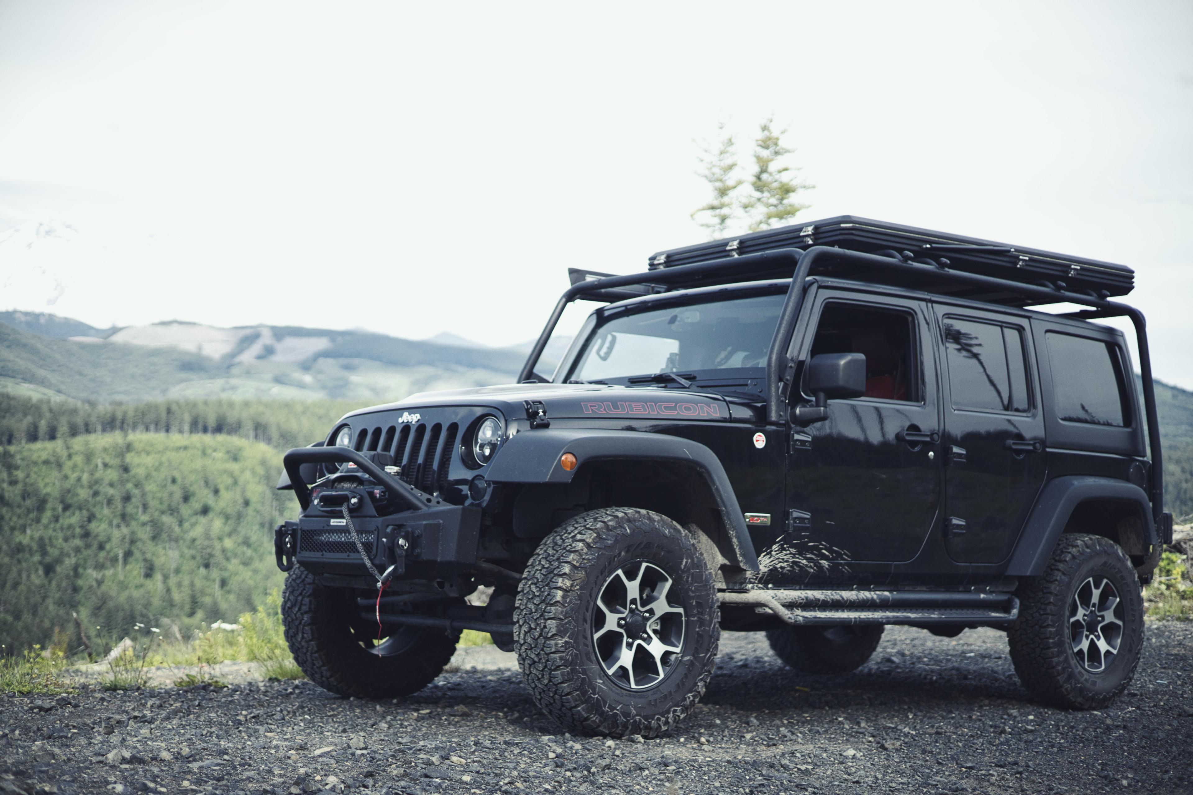 Black Jeep Rubicon parked at a mountain overlook above a forested valley